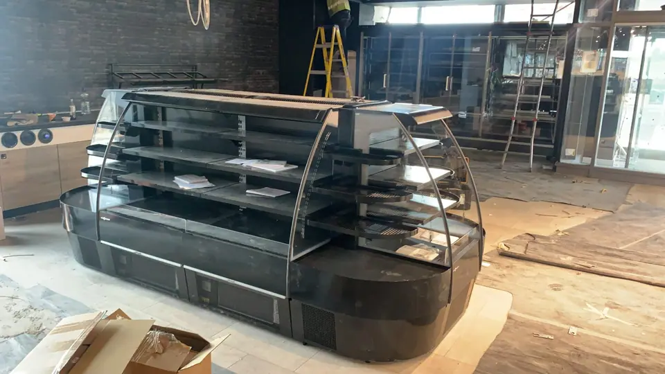 Open-front refrigerated display cabinet being installed in a shop